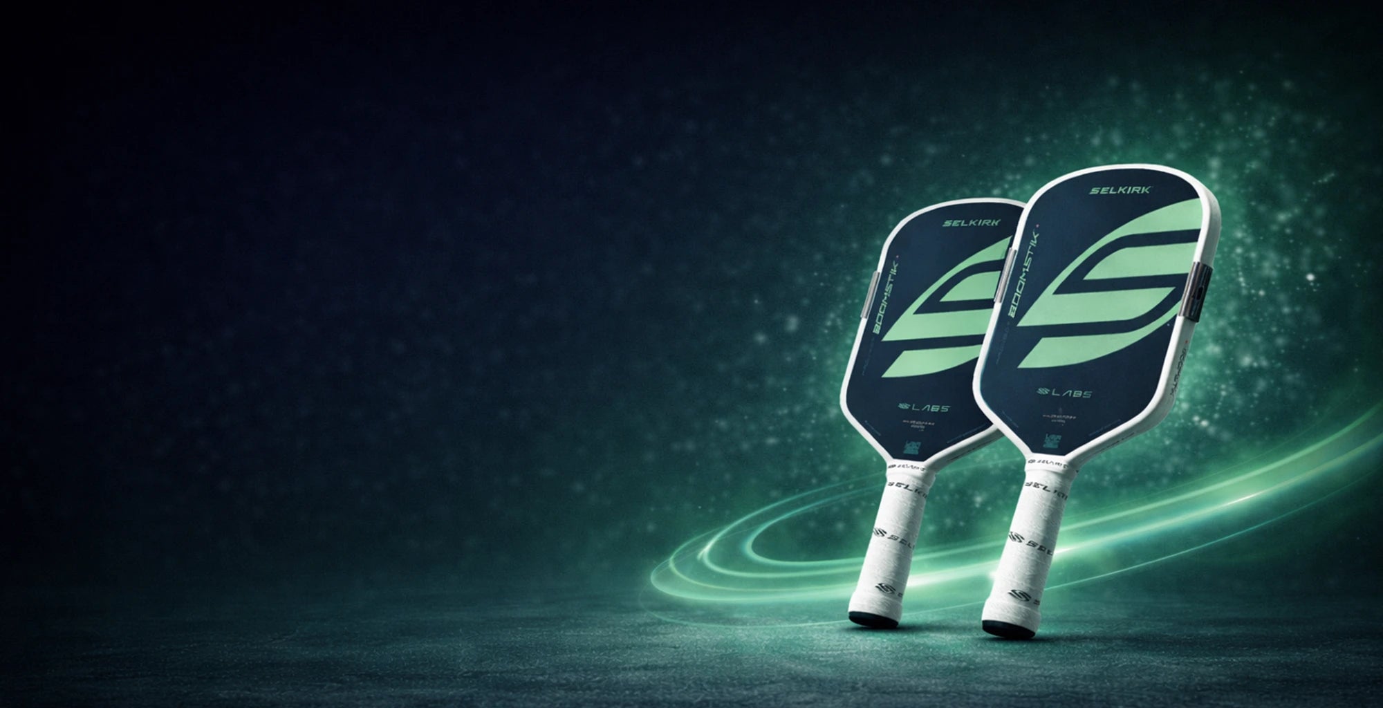 Two Boomstik pickleball paddles with a glowing green effect on a dark background
